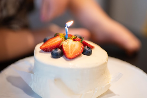 Dekorierter Obstkuchen zum Geburtstag, der eine Kerze anzündet