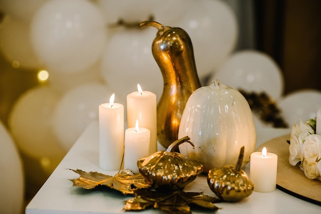 Dekorierter Tisch für die Hochzeit Weiße Luftballons, Kerzen, Herbstblätter und kleine Kürbisse Herbstlage und Halloween-Dekoration