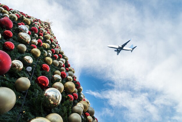 Dekorierter Weihnachtsbaum und Flugzeug im blauen Himmel
