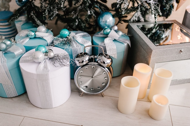 Dekoriertes Weihnachtsinterieur. Baum mit Geschenkboxen, Uhr, Kerzen in einem weißen Raum. Dekor. Fröhliche Weihnachten. Das Konzept der Winterferien.