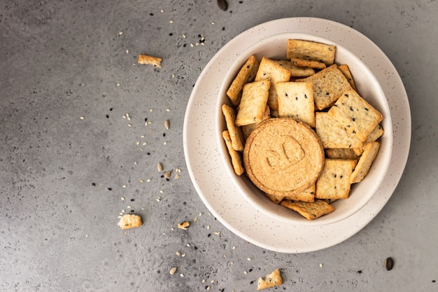 Delgado crujientes galletas integrales con semillas en hormigón gris.