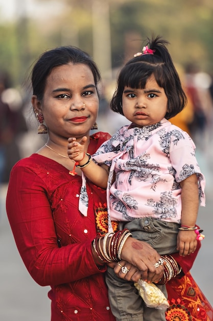Delhi India 02272023 Una mujer en un sari rojo sostiene a un niño pequeño en sus brazos
