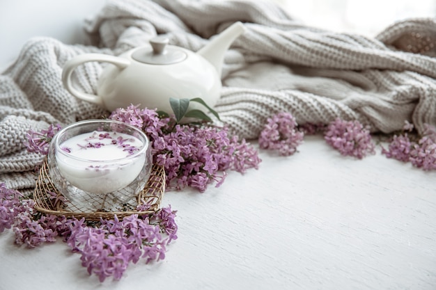 Delicada composição de primavera com flores lilás, um copo de leite e um elemento de malha