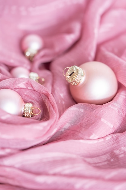 Delicadas decoraciones navideñas de color rosa sobre un fondo de tela de seda rosa el concepto de unas vacaciones