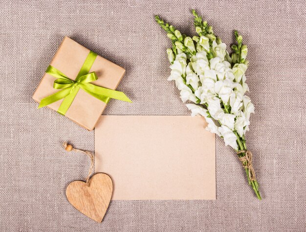 Delicadas flores blancas, caja de regalo y corazón. Fondo romántico Carta de amor y flores. Fondo de papel limpio Copia espacio