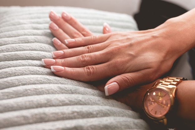 Foto delicadas manos femeninas con una hermosa manicura francesa.