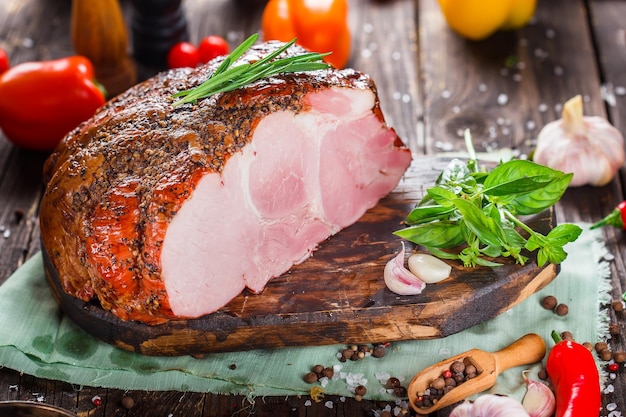Delicadeza de carne, carne de porco cozida bonita, inteira ou fatiada em uma tábua de corte de cozinha, especiarias