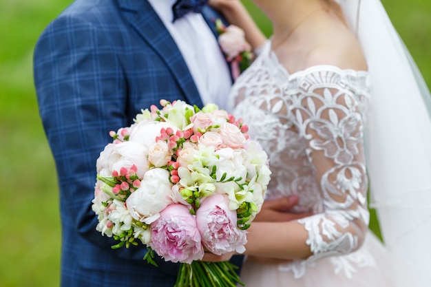 Un delicado y muy hermoso ramo de rosas, peonías, eustoma e hidrogenación sobre un fondo de vegetación. Novia florística en colores rosa y blanco. Mango decorado con encaje y llave.