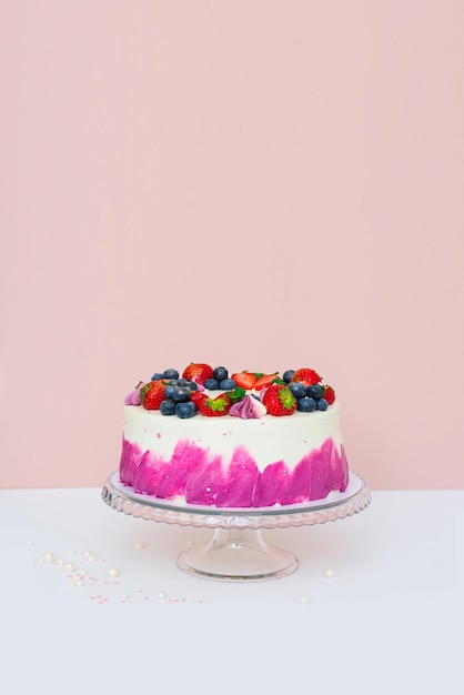 Delicado pastel decorado con bayas frescas, fresas y arándanos sobre un fondo claro y liso