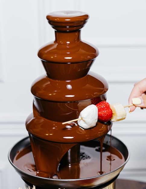 Deliciando-se com Marshmallow de Sobremesa de Chocolate Doce regado com chocolate de uma fonte de chocolate