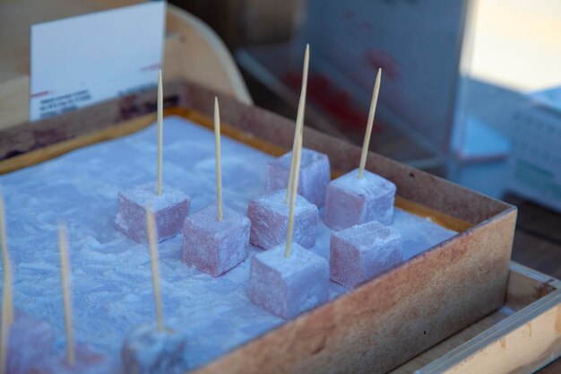 delicias turcas blancas con pistacho sumergido en palitos en una caja de madera.