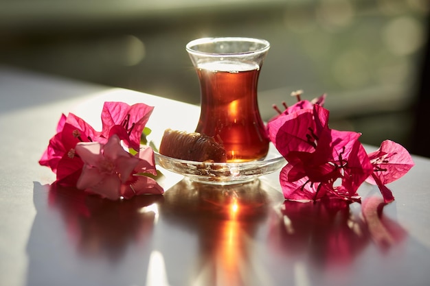 Delicias turcas y vaso tradicional de té turco con flores de buganvilla Concepto de cena romántica Bebida relajante y relajante Concepto de viaje a Turquía Bebida relajante brillante