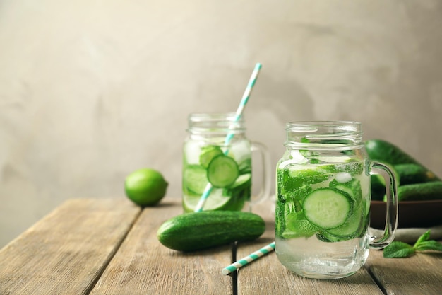 Foto deliciosa agua refrescante con menta y pepino en un frasco de mampostería en una mesa de madera