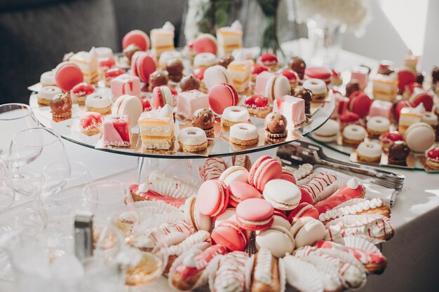 Foto deliciosa barra de caramelo rosa en la recepción de la boda postres rosas y blancos, macarons y cupcakes en el stand mesa dulce moderna en la boda o baby shower concepto de catering de lujo