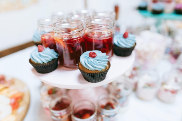 Deliciosa barra de dulces para recepción de bodas Mesa de postres para una fiesta de bodas Pasteles con frambuesas y mermelada de fresax9xA