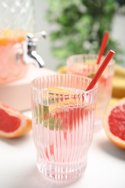 Deliciosa bebida refrescante con pomelo en mesa blanca