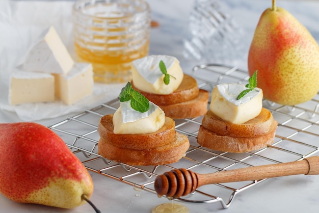 Foto deliciosa bruschetta com camembert de pêra caramelizada ou queijo brie, mel e hortelã sobremesa de frutas crostini de torrada de pão café da manhã saudável para gourmets espaço de cópia de foco seletivo