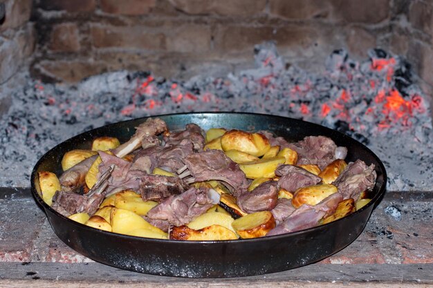 Foto deliciosa carne a la parrilla con patatas en una sartén a fuego abierto