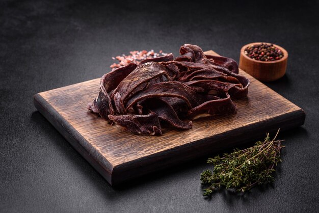 Deliciosa carne seca salada cortada en rodajas como aperitivo para la cerveza sobre un fondo de hormigón oscuro