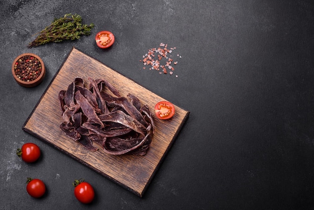 Deliciosa carne seca salada cortada en rodajas como aperitivo para la cerveza sobre un fondo de hormigón oscuro