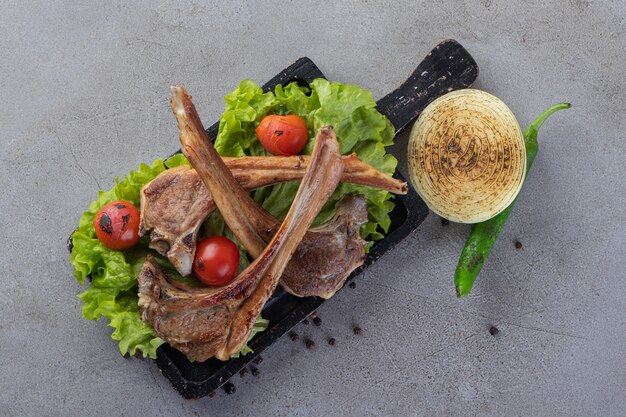 Deliciosa carne con verduras frescas colocadas sobre una mesa de piedra.