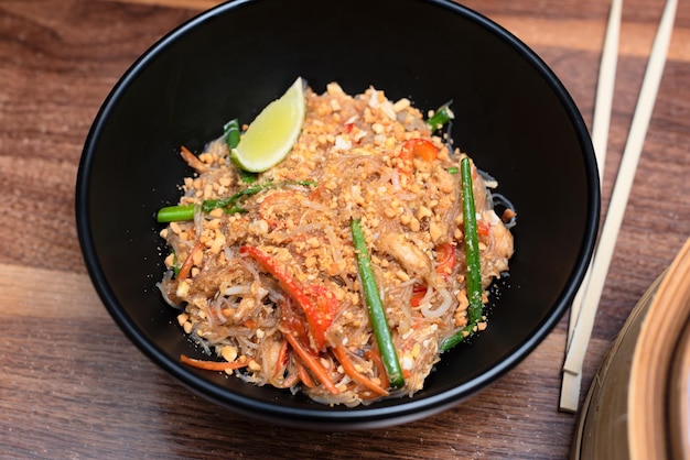 Deliciosa comida asiática wok com macarrão com pauzinhos no fundo de madeira Foco seletivo Conceito de comida asiática