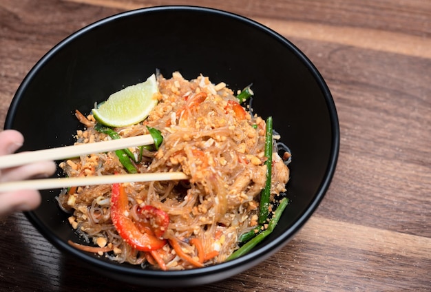 Deliciosa comida asiática wok con fideos con palillos sobre fondo de madera Enfoque selectivo Concepto de comida asiática