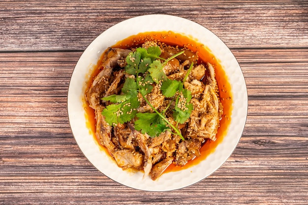 Deliciosa comida chinesa, frango com óleo de pimenta no prato, na mesa de grãos de madeira