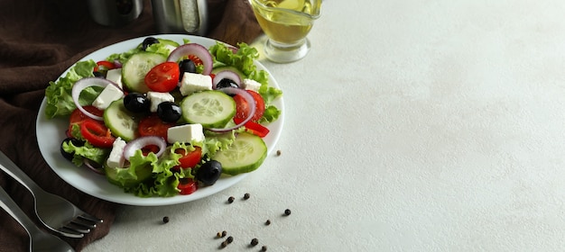 Deliciosa comida con ensalada griega sobre la superficie con textura blanca