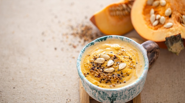 Deliciosa composición con sopa de calabaza en un hermoso plato de cerámica. Comida de temporada.