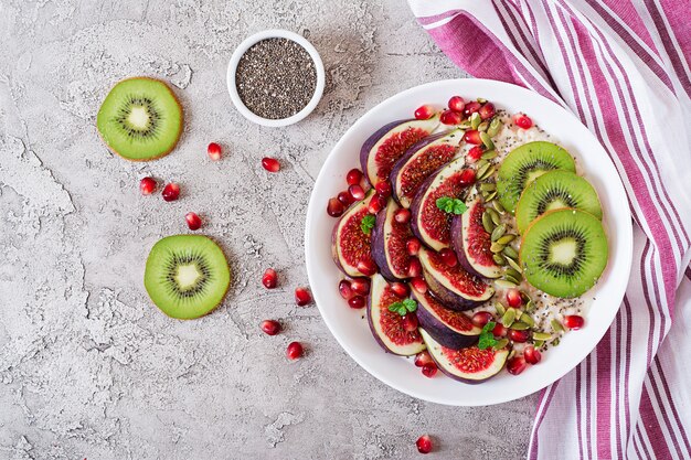 Deliciosa e saudável aveia com figos, kiwi e romã. Café da manhã saudável. Comida de fitness. Nutrição apropriada. Postura plana. Vista do topo.