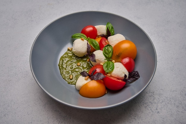 Deliciosa ensalada caprese italiana con tomates maduros piñones albahaca y queso mozzarella en gris