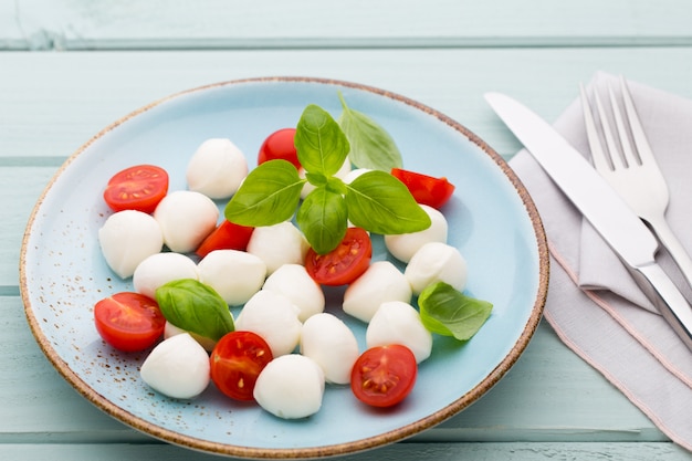 Deliciosa ensalada caprese con tomates cherry maduros y mini bolas de queso mozzarella con hojas de albahaca fresca.