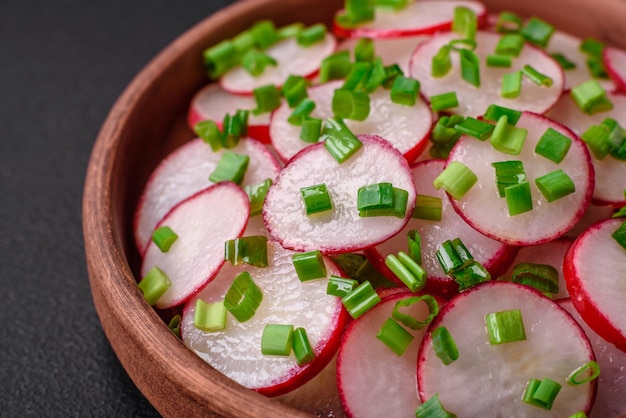 Foto deliciosa ensalada fresca de rábanos en rodajas con cebollas verdes, sal y aceite de oliva