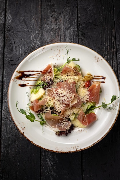 deliciosa ensalada en un plato sobre una mesa oscura