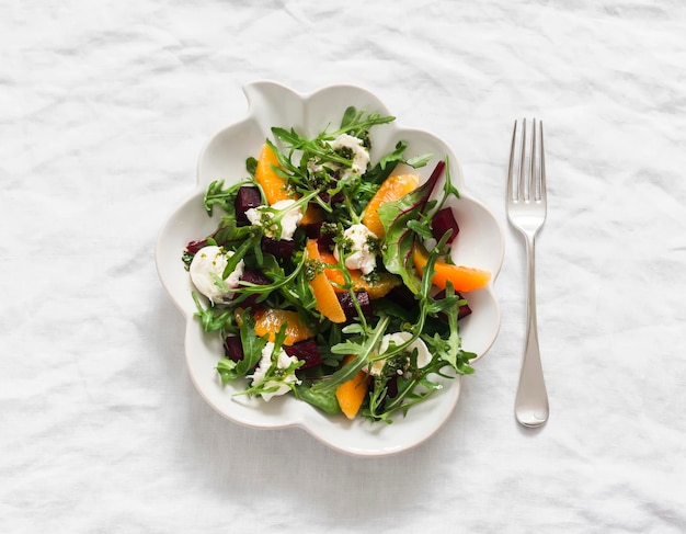 Deliciosa ensalada con queso arugula de remolacha y naranjas en un fondo claro vista de arriba