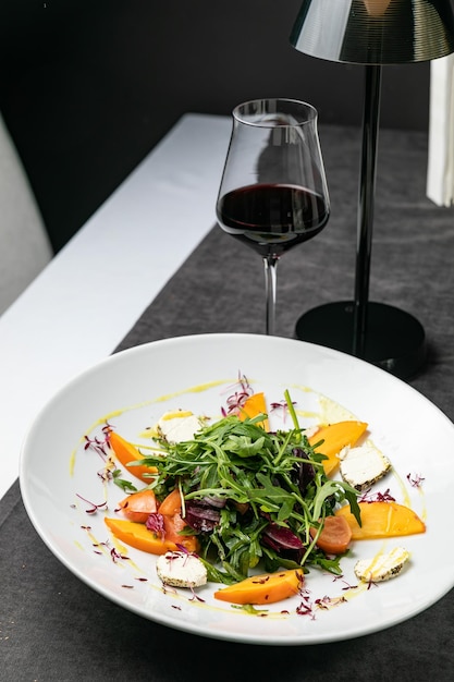 Deliciosa ensalada con rúcula de higos y queso de cabra en la vista superior del plato blanco