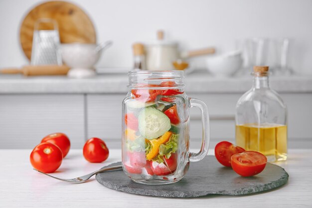 Deliciosa ensalada de verduras en tarro de albañil en la mesa de la cocina