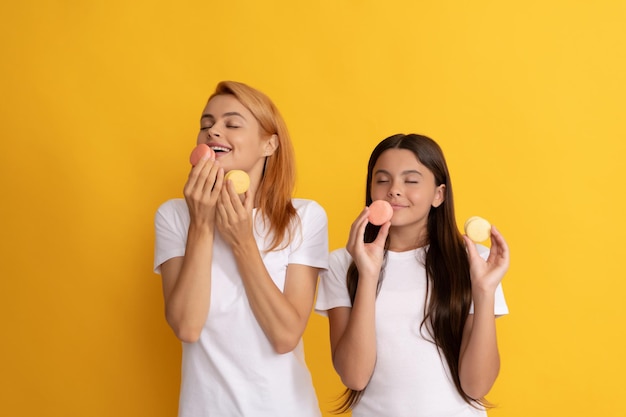 Deliciosa familia cuidado dental pastelería galletas divertida madre e hija comen postre panadería macaroon galleta confitería dulces pasteles franceses feliz niño y mamá sostienen macaron francés goloso