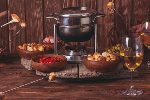 Deliciosa fondue de queso en una horquilla sobre un soporte de madera