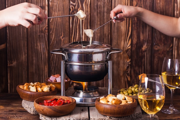 Deliciosa fondue de queso en una horquilla sobre un soporte de madera