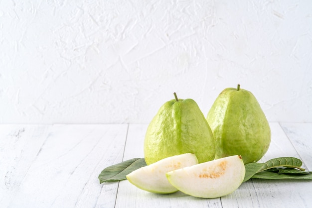 Deliciosa goiaba com folhas frescas isolada em uma mesa de madeira branca brilhante