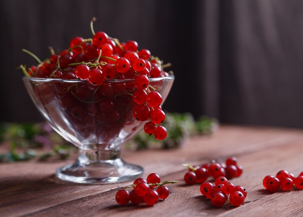 Foto deliciosa grosella roja madura en un florero de vidrio sobre una mesa de madera