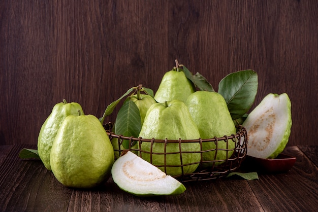 Deliciosa guayaba hermosa con hojas frescas aisladas sobre fondo de mesa de madera, de cerca.