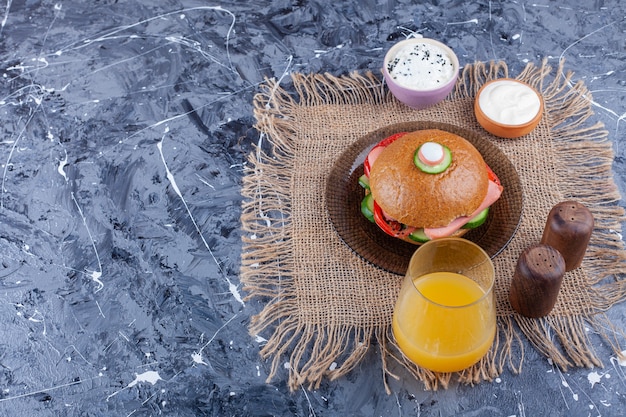 Deliciosa hamburguesa casera y vaso de jugo fresco en la mesa de mármol.