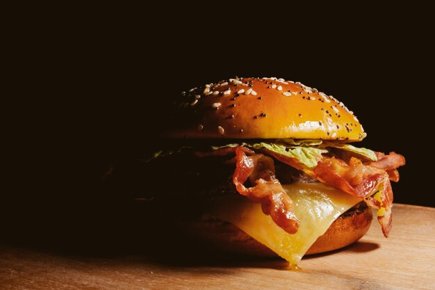 Deliciosa hamburguesa jugosa en una tabla de madera en un procesamiento de fotos vintage de fondo negro