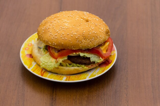 Deliciosa hamburguesa o sándwich en un plato sobre la mesa de madera. Hamburguesa casera sobre fondo de madera