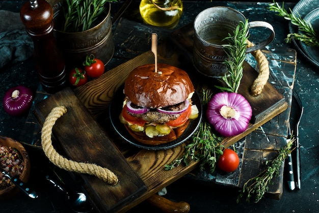 Deliciosa hamburguesa a la parrilla con chuleta de ternera cebolla y verduras en el viejo fondo oscuro