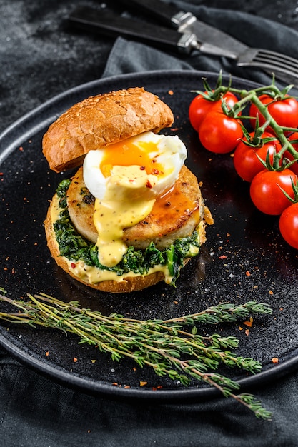 Deliciosa hamburguesa de pescado con filete de pescado, huevo y espinacas en un bollo de brioche. .