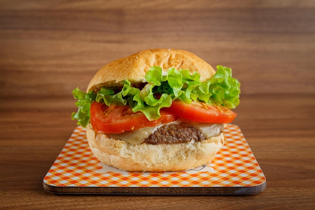 Deliciosa hamburguesa sobre fondo de madera Hamburguesa con tomate, lechuga, carne y queso